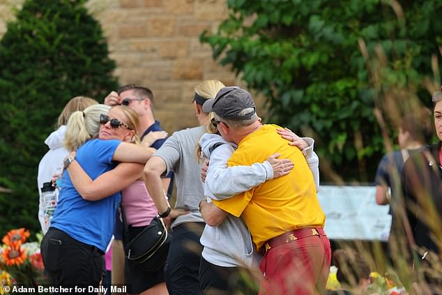 Community members gather at the scene of the mass shooting where two children were killed