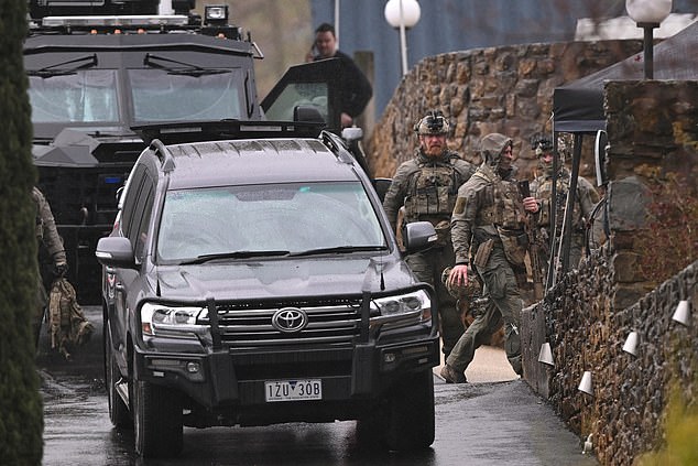 Heavily armed police gather at a staging point during a search for a fugitive linked to the murder of two police officers, in Porepunkah on August 29, 2025. Australian police said on August 28, that they will not rest until they catch a 56-year-old gunman who fled into the bush two days earlier after allegedly killing two officers. Detectives said they were speaking to the man's partner and searching rugged, forested terrain near the small town of Porepunkah, in the northeast of Victoria state. (Photo by William WEST / AFP) (Photo by WILLIAM WEST/AFP via Getty Images)