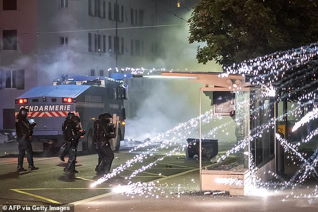 Fireworks explode near police officers in riot gear in Lausanne, on August 25, 2025
