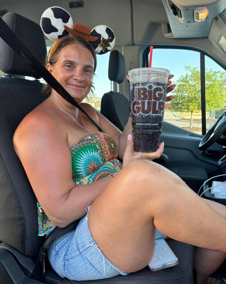 Woman in a car holding a large soda.