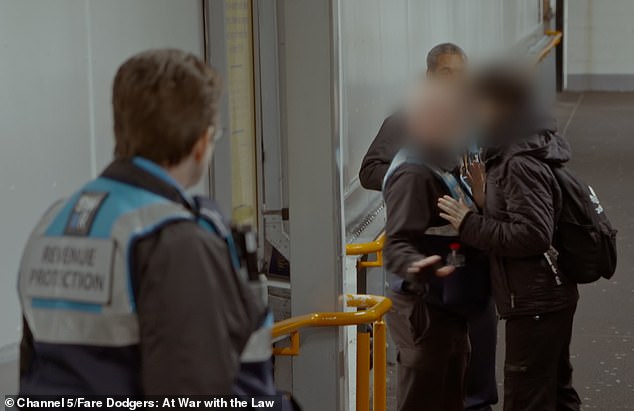 A passenger tries to push past a revenue protection officer at Weybridge station in Surrey