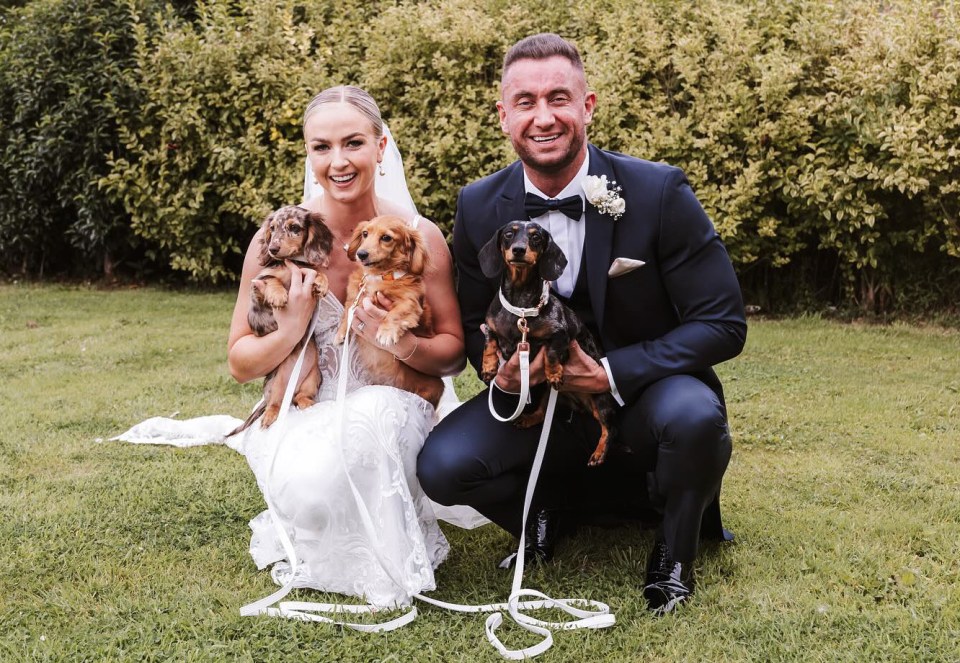 Bride and groom kneeling with their two dachshunds.