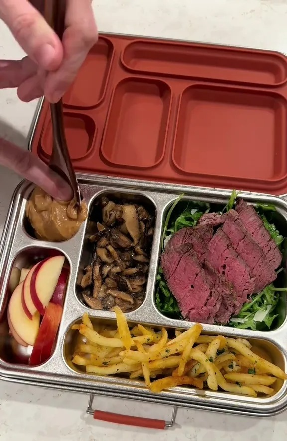 Luxury packed lunch: steak, fries, mushrooms, apple slices, and a dip.