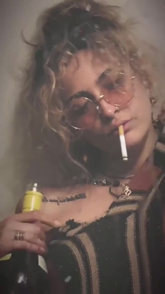 Photo of Paris Jackson smoking a cigarette and holding a bottle of wine.