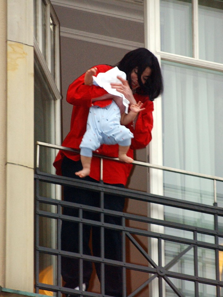 Michael Jackson holding his son on a balcony.