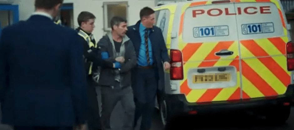 Man in handcuffs being escorted by police.