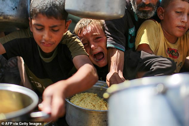 People try to get rice from a charity kitchen providing food for free in the west of Gaza City, on August 28, 2025