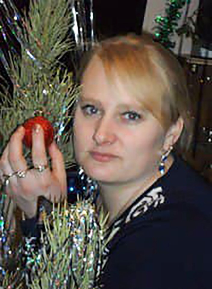 Woman holding an ornament near a Christmas tree.