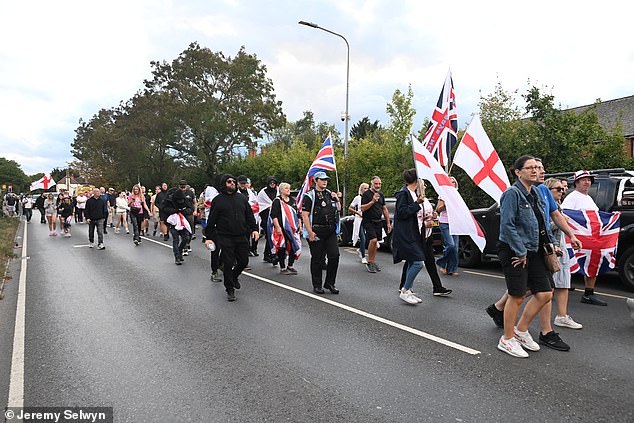 Protesters march towards The Bell Hotel this evening, waving England flags and Union Jacks