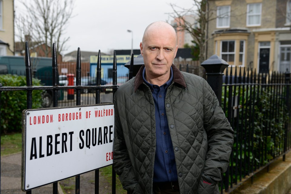 Paul Usher as Danny Hardcastle in EastEnders, standing by an Albert Square sign.