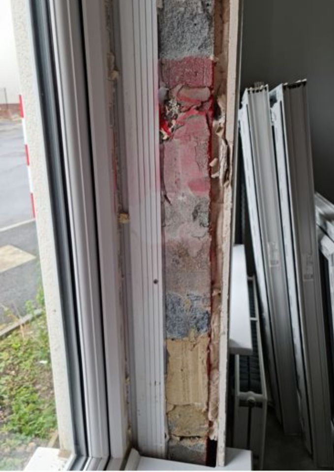 Damaged window frame and exposed brickwork in a house.