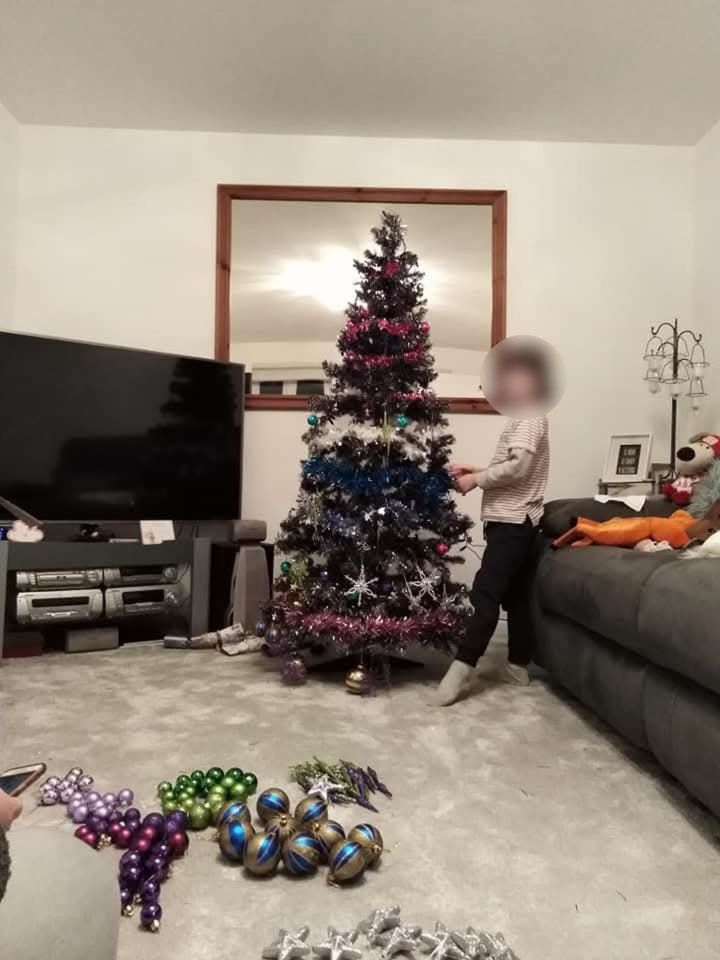 A child decorating a Christmas tree in a living room.