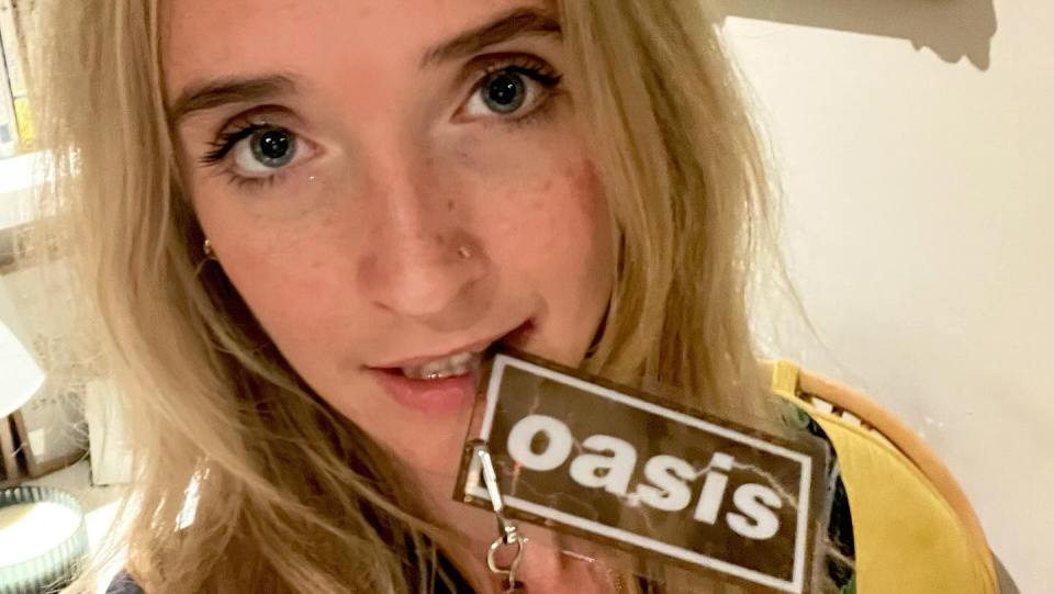Close-up of a person holding an Oasis keychain.