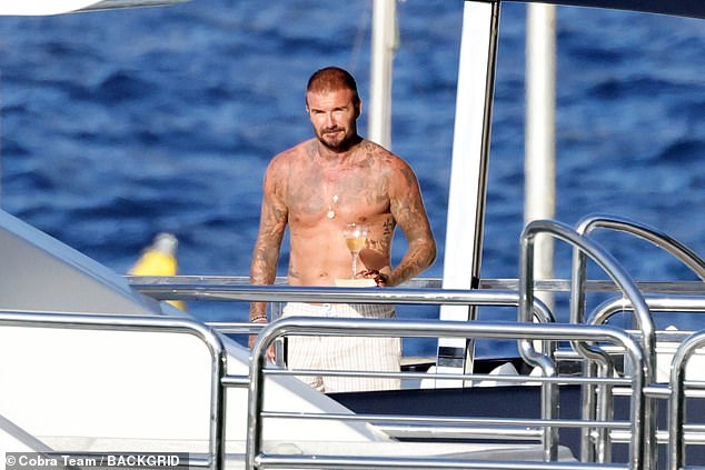 The former England captain displayed his many tattoos as he went shirtless while carrying his drink outside to enjoy in the sunshine