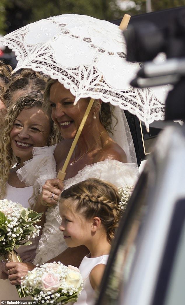 The bride shielded herself from the sun beneath a vintage umbrella