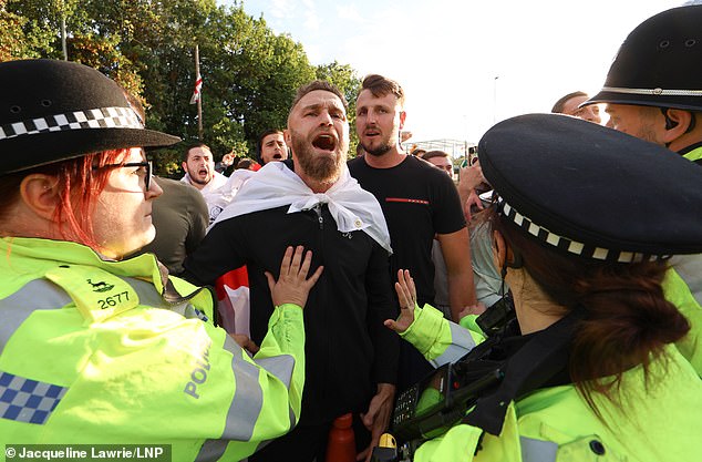 A man appears to be shouting as he wears an English flag at protests in Cheshunt today