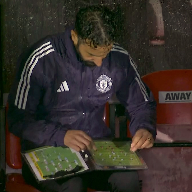 Ruben Amorim reviewing game strategy in a rainy dugout.