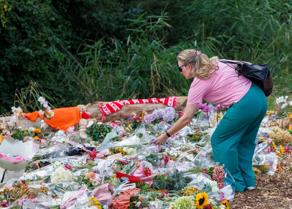 Woman adding flowers to a large memorial.
