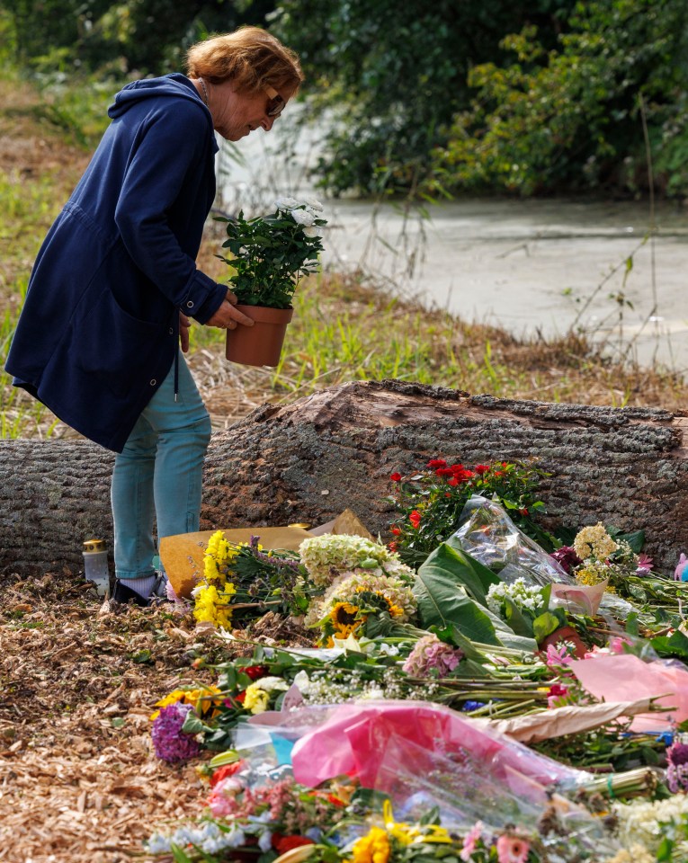 Woman adding flowers to a memorial.