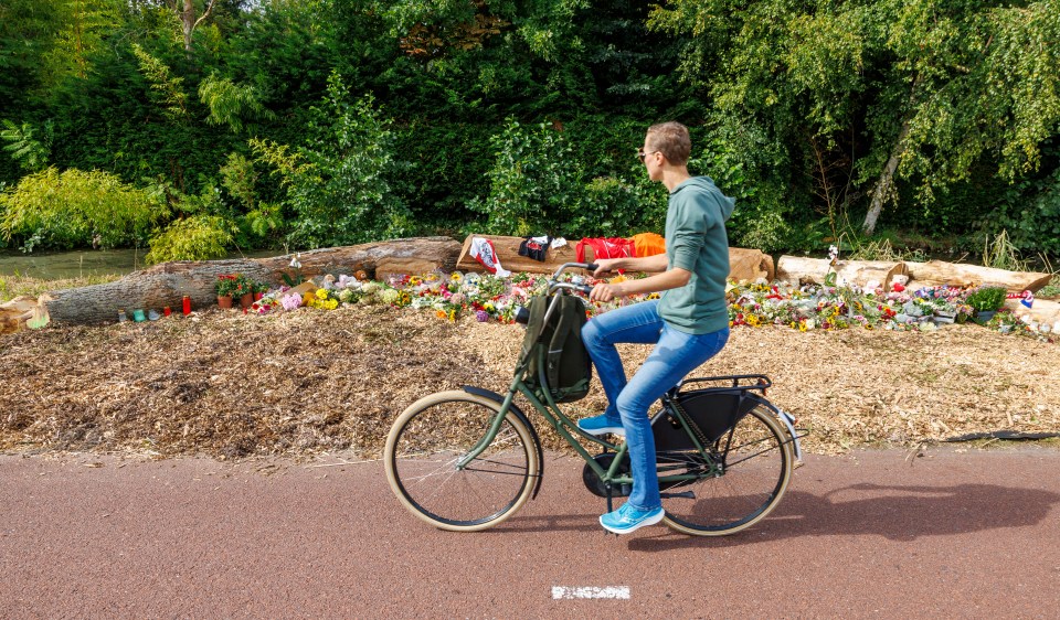 Person cycling past a floral tribute.