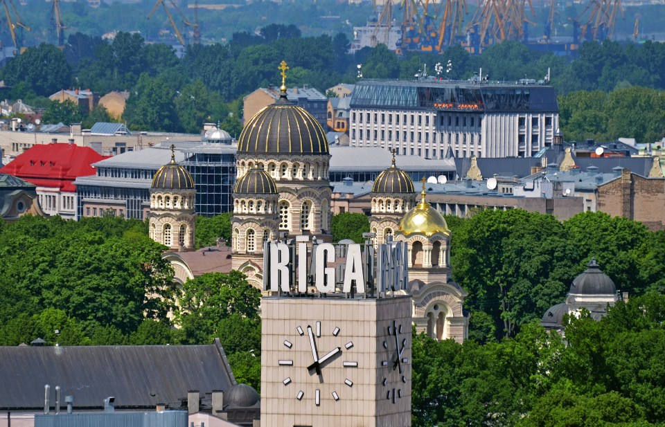 Aerial view of Riga, Latvia, featuring the Nativity Cathedral and a clock tower with "Riga" signage.