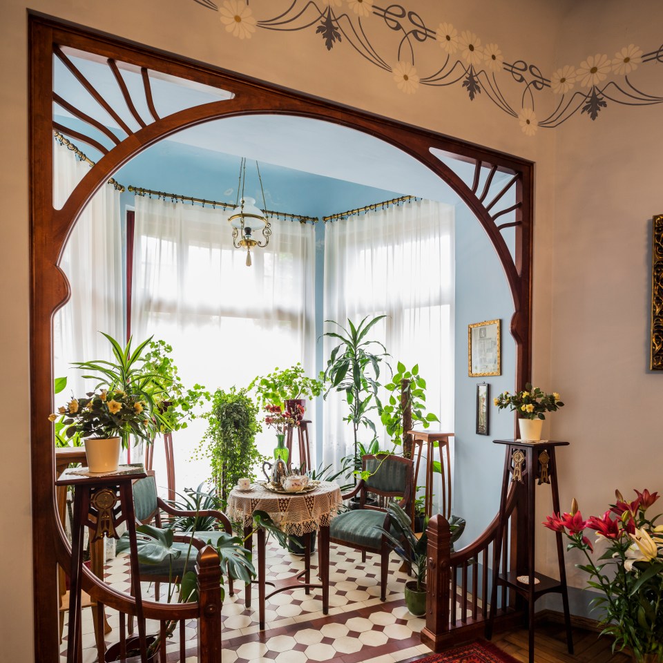Art Nouveau sitting room with plants and a tea set.
