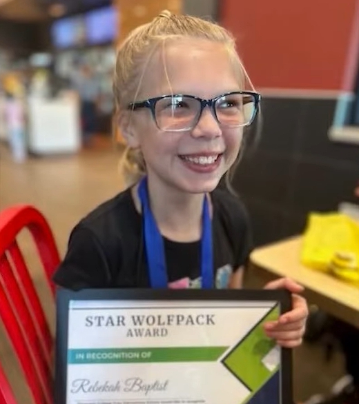 Rebekah Baptiste holding a Star Wolfpack Award.