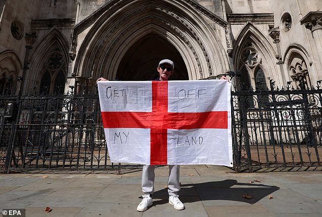 A protester holding an England flag stands outside the High Court in London yesterday