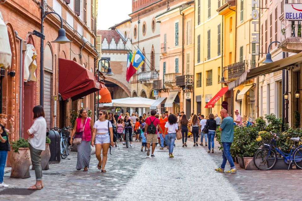 Tourists walking down a cobblestone street in Ravenna, Italy.