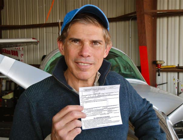 Pilot holding aircraft registration after water landing.