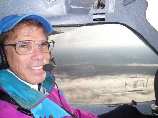 Pilot in cockpit above clouds.