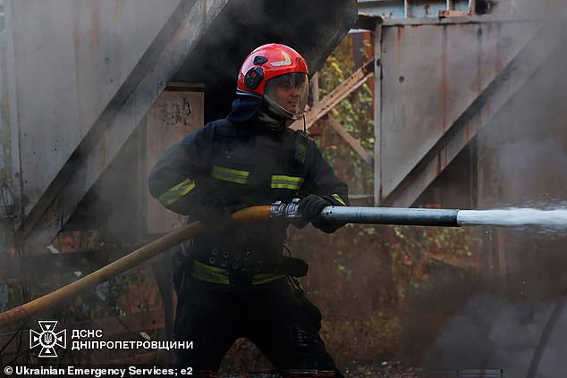 A firefighter is seen trying to put out flames in the Dnipropetrovsk region after an attack from Russia damaged infrastructure and private housing