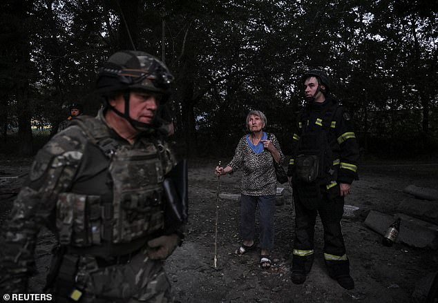 A firefighter and a resident stand at the site of an apartment building hit during a Russian drone and missile strike, amid Russia's attack on Ukraine, in Zaporizhzhia, Ukraine August 30, 2025