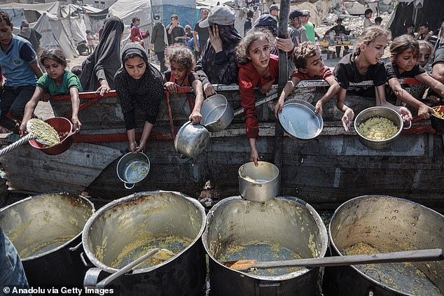 Palestinians, including children, try to receive hot meals, distributed by charity organizations, as people struggle to access food due to Israeli food blockade in Gaza City, Gaza on August 30, 2025