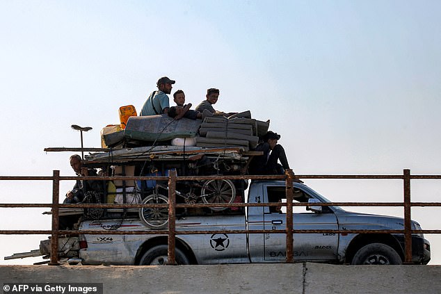 Displaced Palestinians fleeing south ride atop a truck with belongings along the coastal road through the Nuseirat camp for Palestinian refugees in the central Gaza Strip on August 30