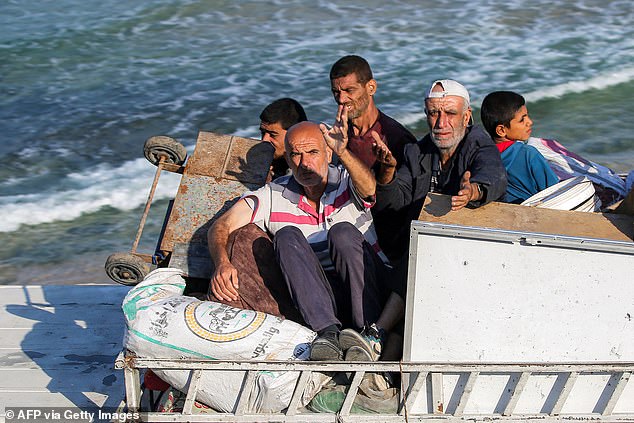 Displaced Palestinians fleeing south react as they ride in the back of a truck with belongings along the coastal road through the Nuseirat camp for Palestinian refugees in the central Gaza Strip on August 30
