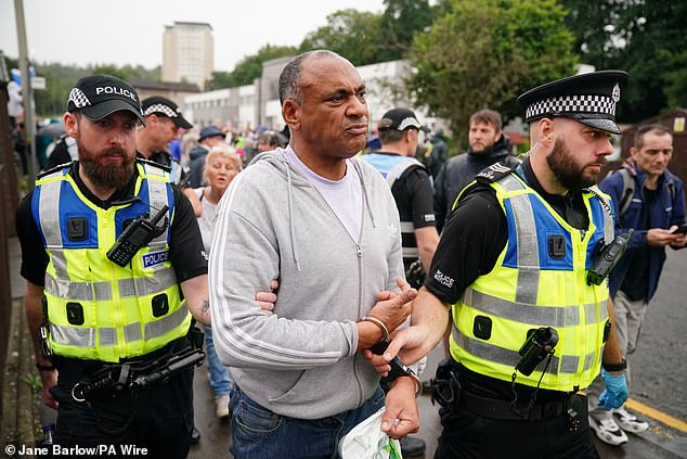 A man is handcuffed and led away by police during a Save Our Future & Our Kids Futures protest