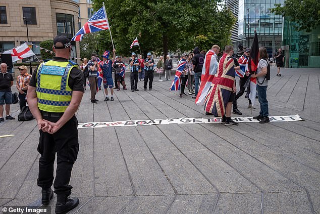 Demonstrators are seen wearing Union Jack and England flags during an anti-immigration protest outside the New Bridge Hotel in Newcastle on Saturday