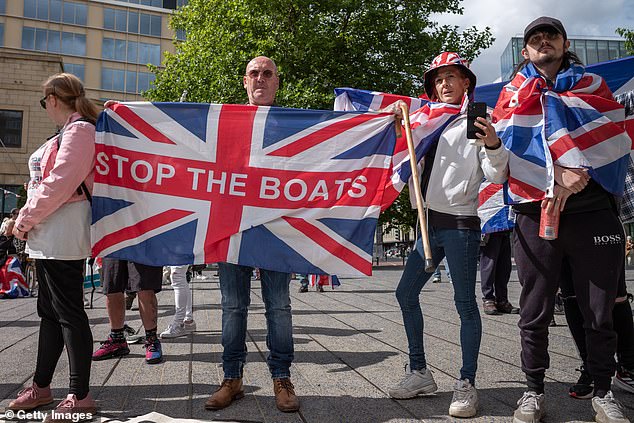 An anti-immigration protester poses with a Union Jack flag with the slogan: 'Stop the boats'