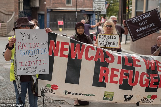 Counter-protesters hold banners reading: 'Newcastle welcomes refugees' and 'Your racism isn't patriotic it's idiotic'
