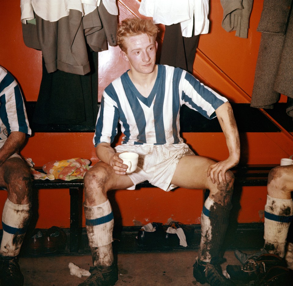 Denis Law, Huddersfield Town player, drinks tea in the locker room after a game.