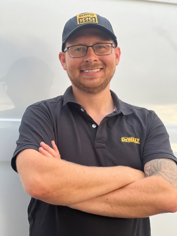 Portrait of a smiling man wearing a DeWalt hat and polo shirt.