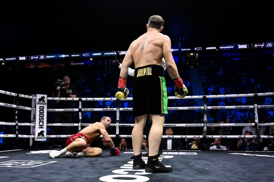 Darren Till stands over a fallen Luke Rockhold in a boxing match.