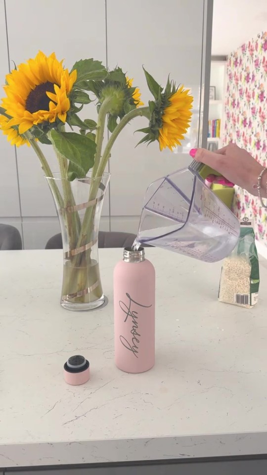 Water being poured into a pink water bottle.