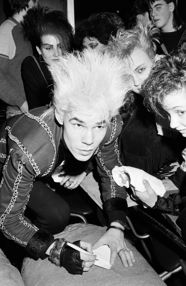 Black and white photo of Ray Mayhew of Sigue Sigue Sputnik signing autographs at a concert.