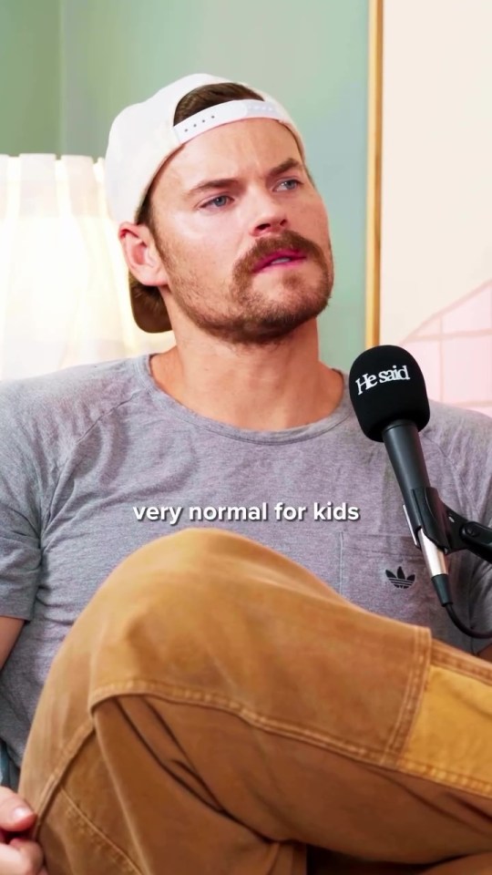 Man in a baseball cap speaking into a microphone.