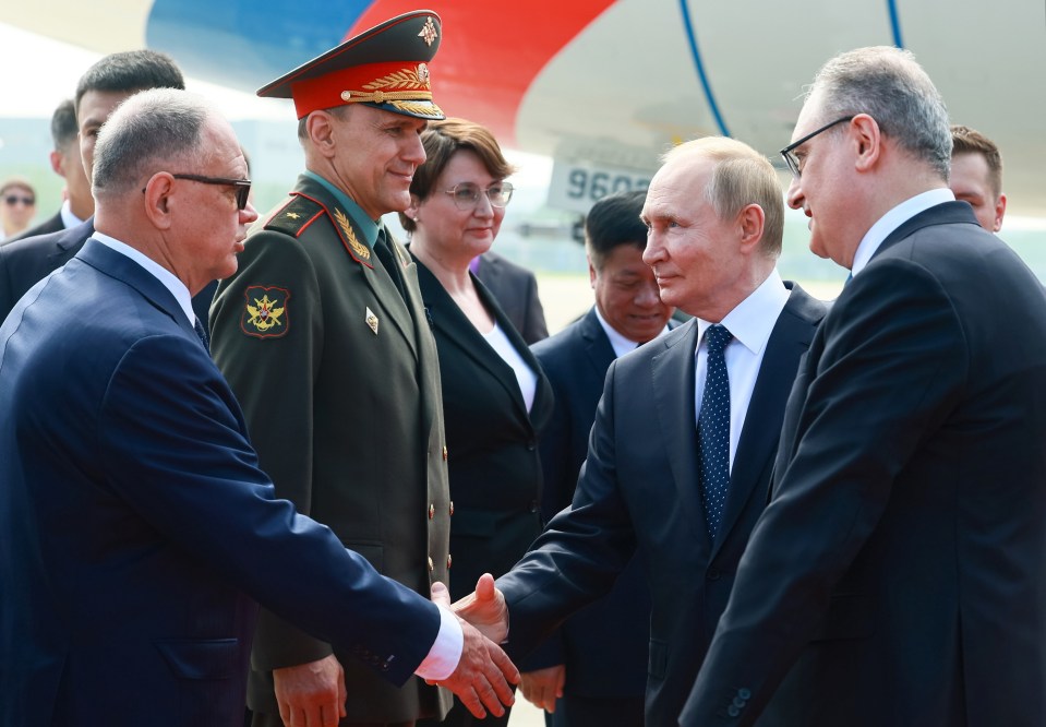 Vladimir Putin shaking hands with officials upon arrival at Tianjin's Binhai International Airport.