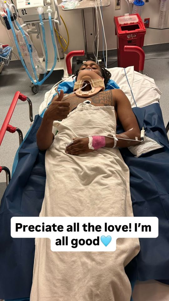 Taylor Williams in a hospital bed, giving a thumbs-up.