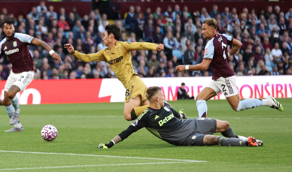 Aston Villa's goalkeeper dives to try and stop a Crystal Palace player from scoring.