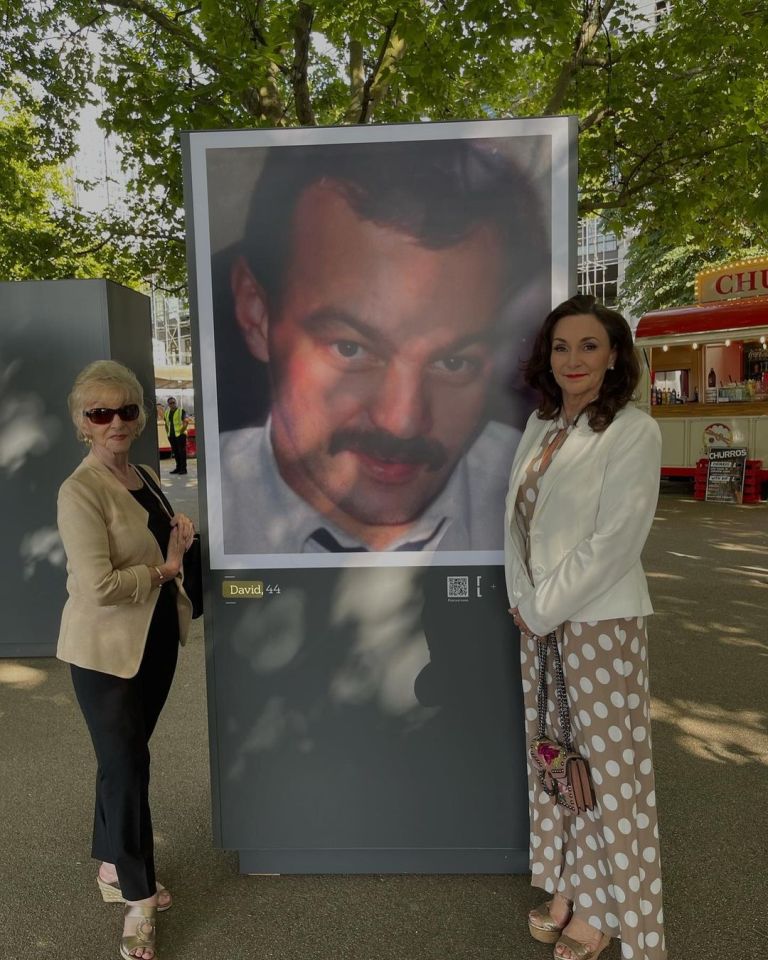Shirley Ballas and another woman stand beside a large photo of her deceased brother.